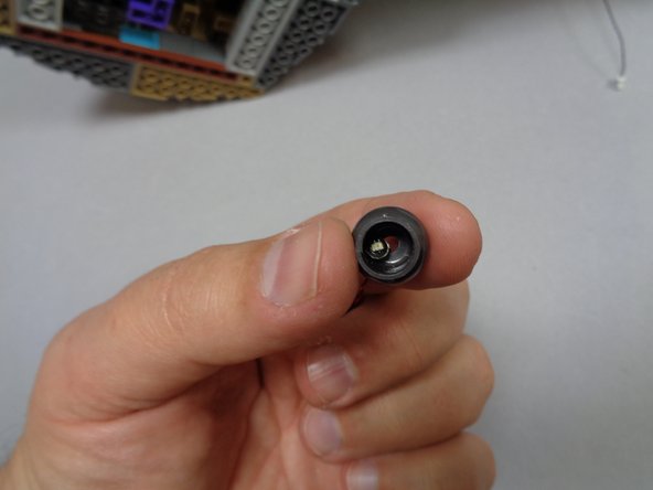 As shown in the second photo, the cauldron in your kit may have the orange light pre-mounted, or the orange light may be supplied loose in the bag.  If your light is not pre-mounted, feed its power plug down through the bottom of the cauldron as shown, so the light sits in the bottom of the cauldron as shown in the third photo.