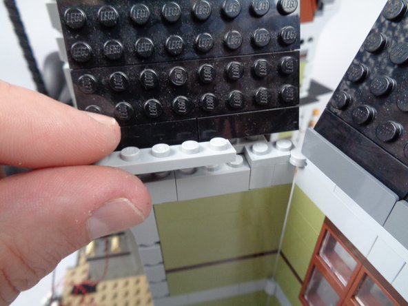 As shown in the photos for this step, re-attach the LEGO parts you removed in the earlier steps to rebuild the wall.