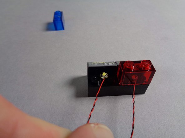 As shown in the second photo, carefully replace the transparent red brick so it covers the Pico LED light, being careful that the light wire passes between, not on top of, the brick's studs.