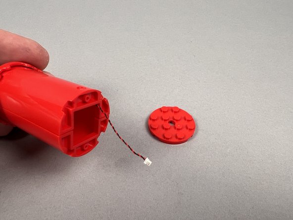 As shown in the first photo for this step, continue passing the light wire down through the middle of the top candle section until its plug comes out the bottom.