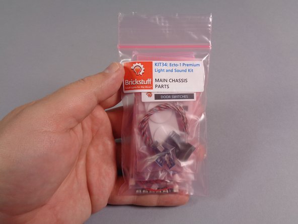 As shown in the first photo for this step, remove the large pink bag labeled &quot;MAIN CHASSIS PARTS&quot; from the Brickstuff kit box.