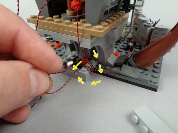 Because the attic light wire is long, you can wrap it several times around the wire base you built earlier, as shown by the yellow arrows in the second photo for this step.