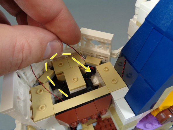 As shown by the yellow dotted line in the third photo, run the spinning room light wire above the spinning room and loop the wire around the top section of the tower, then back down into the spinning room.  This will help prevent the light from being pulled off.