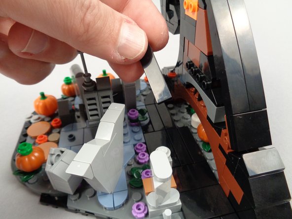 As shown in the first and second photos for this step, remove the two 1x4 black tiles from the base of the wave.