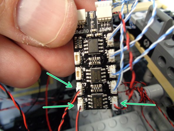 As shown by the three green arrows in the photo for this step, connect the three door frame lights to plugs #5, #6, and #7 on the BRANCH09X adapter board.