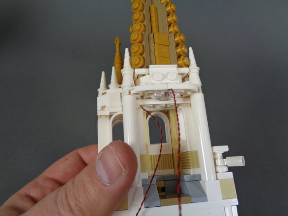 As shown in the second and third photos, carefully re-attach the tower roof.  After the roof has been attached, the two LED light wires should pass out toward the back of the tower as shown in the third photo.