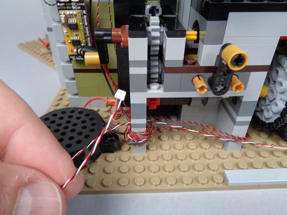 As shown in the second and third photos for this step, pass the 3-wire cable through the holes in the Technic brick, and wrap around several times to secure it.