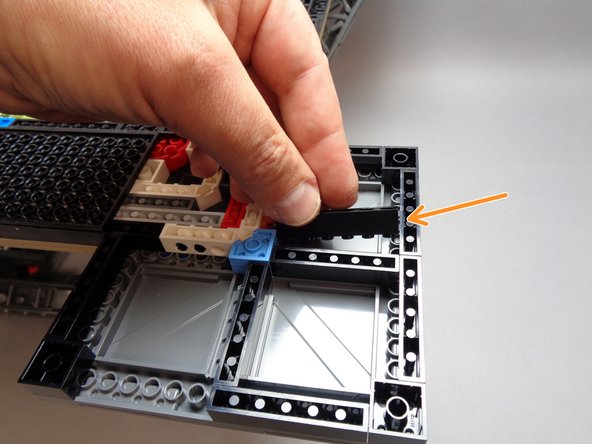 As shown by the orange arrow in the third photo for this step, place the 1x6 brick you just removed in the center of the interior of the foot.