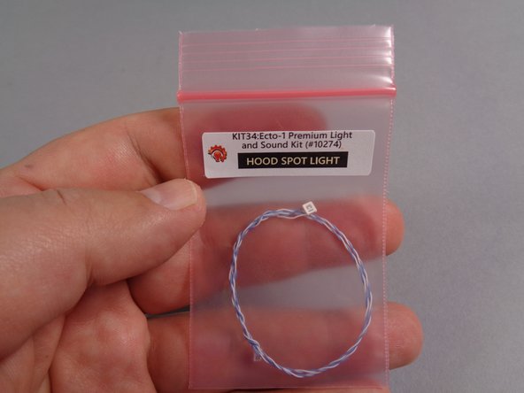 As shown in the first photo for this step, remove the small pink bag labeled &quot;Hood Spot Light&quot; from the &quot;Roof Parts&quot; bag, and position the LED light in the center of the 1x2 plate with clip.