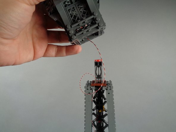 Pull the wire down into the center of the top tower section as you finish re-attaching the broadcast tower section.