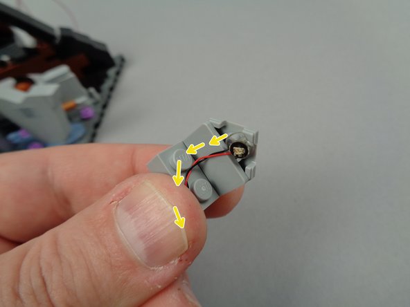 As shown by the yellow arrows in the second photo for this step, run the light wire down the back of the tombstone and between the two studs on the plate.