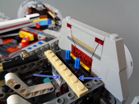 As shown in the first photo, remove the tan 1x8 plate at the end of the docking bay wall and carefully run the top light wires between the studs.