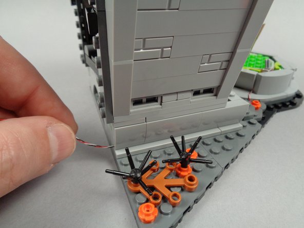 As shown in the first photo for this step, re-attach the rear slope part to the town hall.  The light strip wire should now pass to the rear of the hall as shown.