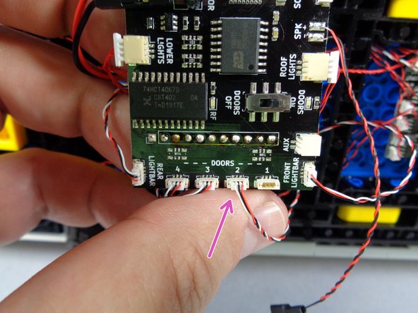 As shown by the purple arrow in the third photo for this step, connect the door switch wire to any of the open DOORS plugs on the main controller.