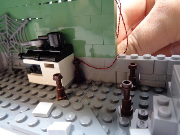 As shown in the second photo, run the oven light wire along the kitchen wall and out the opening in the wall.   The wire should run low enough along the wall that it will be hidden by the table.