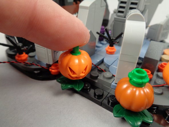 As shown in the third photo, re-attach the pumpkin on top of the LED light and green flower plate.