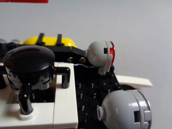 As shown in the second photo for this step, carefully re-attach the red roof LED light assembly to its clip, making sure the light wire passes through the middle and toward the back without being pinched by any part of the clip.