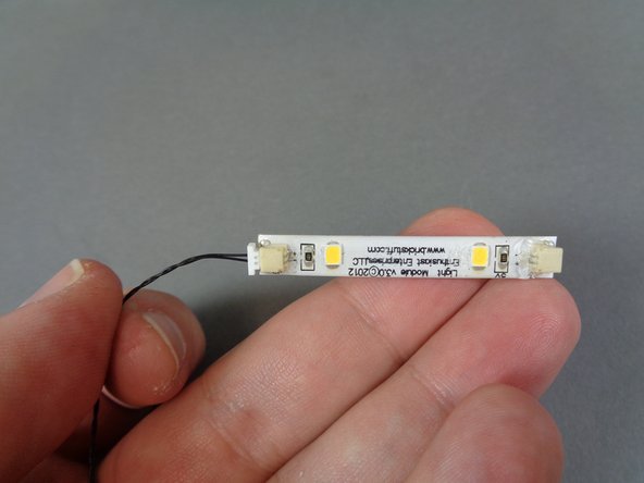 From the &quot;Lower Level Lights and Parts&quot; bag, remove the 6&quot;/15.2cm black connecting cable, the warm white light strip, and the two black LEGO slopes as shown in the first photo.