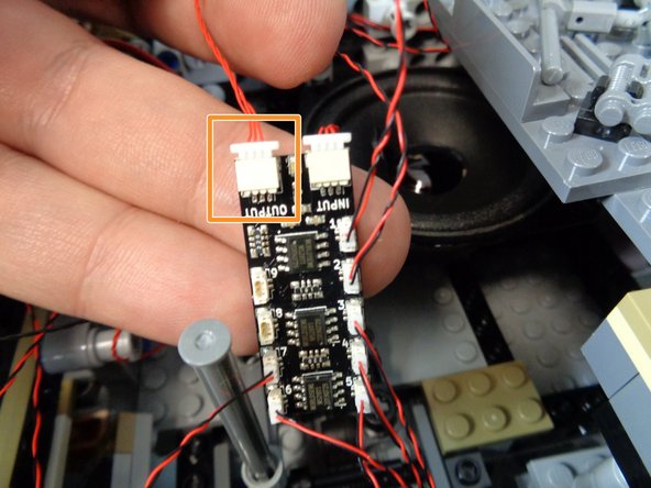 As shown by the orange rectangle in the first photo for this step, take another red 12&quot; 3-wire cable from the Main Control and Connecting Parts bag, and connect one end of the cable to the OUTPUT plug on the second BRANCH09X adapter board.