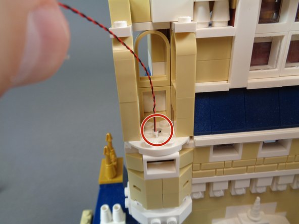 As shown by the red circle in the second photo, pass the light wire down through the hole in the lower round white LEGO plate.