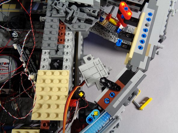 As shown in the photos for this step (and by the red rectangle in the first photo), attach the second black lever to the top of the axle and to the top of the Falcon frame.  This should hold the servo firmly in place, yet allow it to rotate slightly.