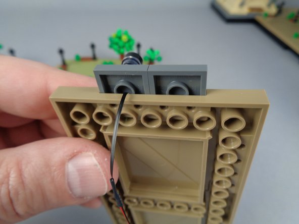 As shown in the third photo for this step, the LED light wire passes under the lamp post and down.