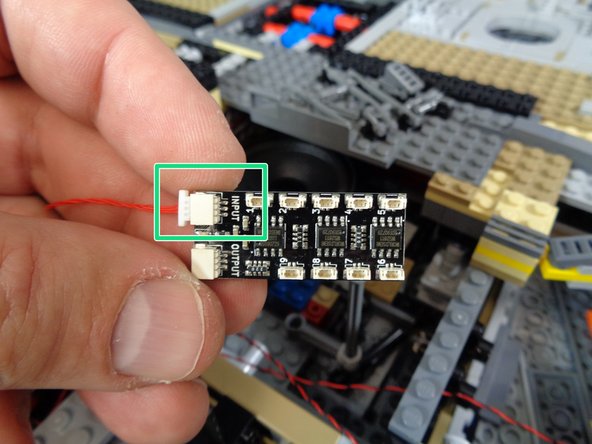 As shown by the orange rectangle in the first photo, connect one end of the red cable to the OUTPUT plug on the first BRANCH09X adapter board (the one with all nine small plugs filled).