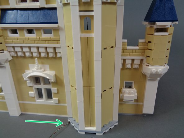 Your castle should now be re-assembled and the only wire visible from the front should be the lower level connecting cable coming through the bottom of the kitchen floor as shown by the green arrow in the second photo.