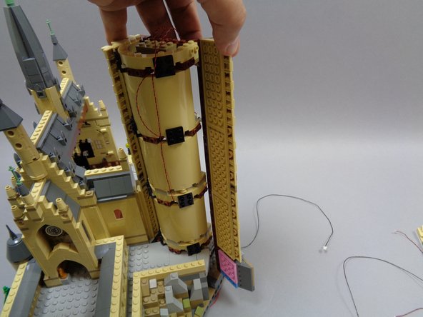 As shown in the first photo, carefully remove the long side panel of the castle tower.  Make sure the entire panel comes off, all the way down to the pink plate as shown.