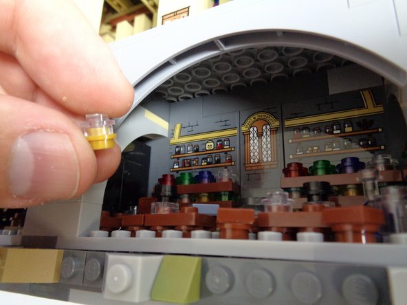 As shown in the photos for this step, remove the small lamp from the Potions Class, remove the transparent clear piece on top, and mount the last warm white light from Bag 10 on the gold base of the lamp.