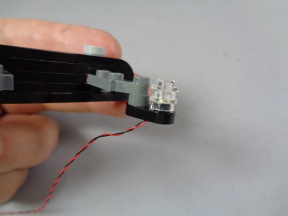 As shown in the third photo for this step, carefully re-attach the transparent round 1x1 plates on top of the LED light.