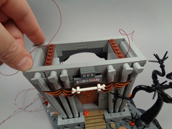 As shown in the photos for this step, re-attach the two long tiles to the top front of the town hall.