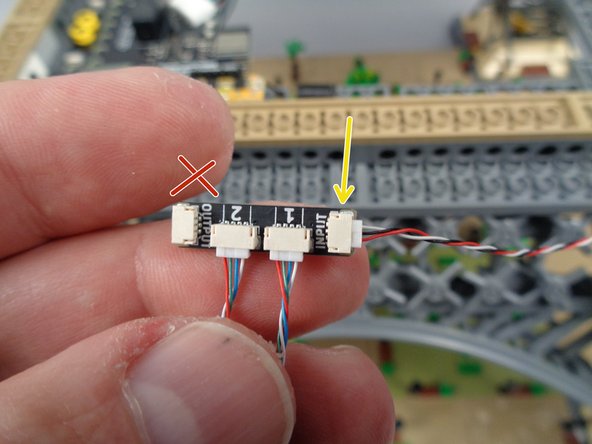 As shown by the yellow arrow in the photo for this step, connect one of the 3-wire control cables to the INPUT plug on one of the adapter boards. (you can select any adapter board as the first in the chain)