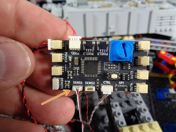 As shown by the green rectangle in the first photo for this step, disconnect the control wire for the engines sound module from the top right plug on the old TRUNK05 controller.