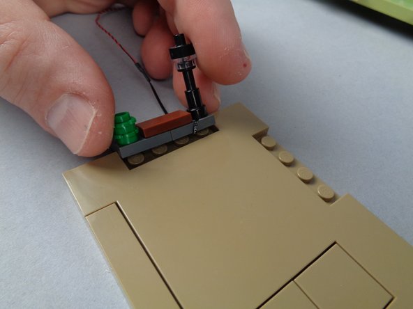 As shown in the first photo for this step, carefully re-attach the lamp post to the base plate.