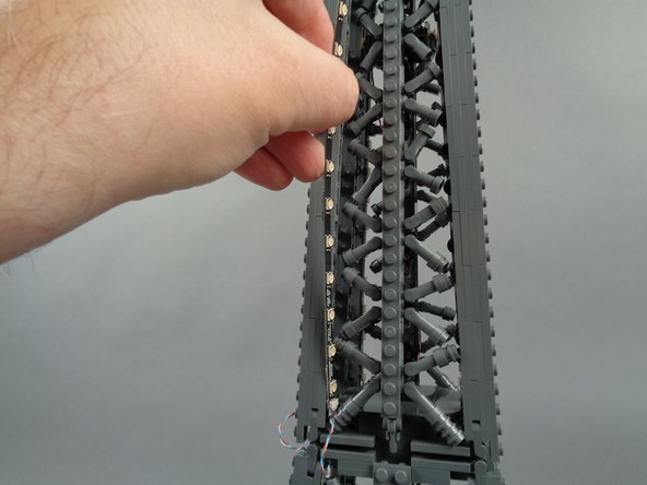As shown in the photos for this step, attach the top of strip #2 to the tower frame, and re-position brace elements as needed to make room for the LED lights and strip.