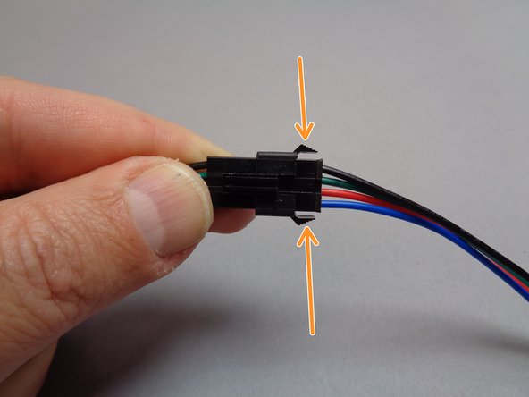 To disconnect, press down on the latch on the top of the plug as shown in the second photo while at the same time pressing in on the two tabs on the side of the plug as shown in the third photo.