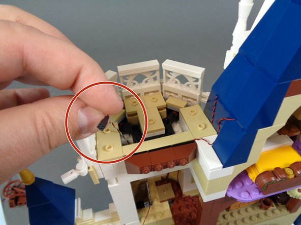 As shown by the photos in this step, take the end of the wire with the black &quot;female&quot; connector (without gold pins) and feed it up through the spinning room and through the top of the top open section as shown in the third photo.