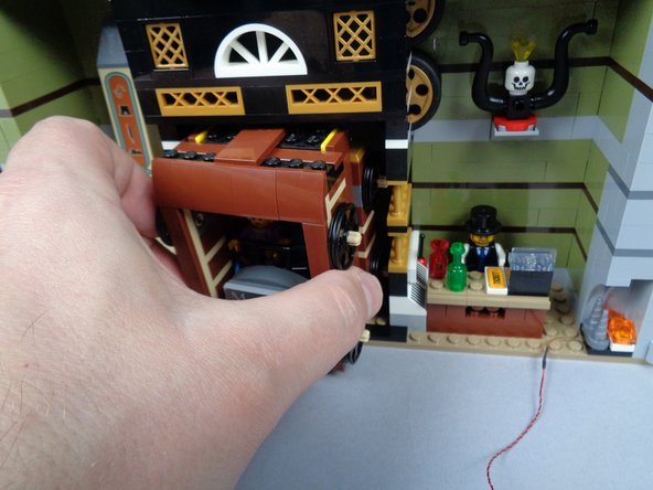 As shown in the three photos for this step, remove the two side brackets holding the elevator in place, then carefully remove the elevator car.  Set aside.