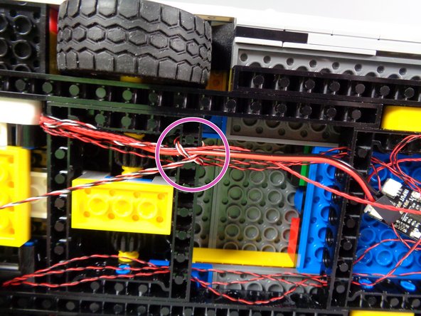 Because the plugs for the roof lights control wire and the motor wire are too thick to pass through the holes in the black Technic frame, you will use the two lightbar control wires to hold them in place.