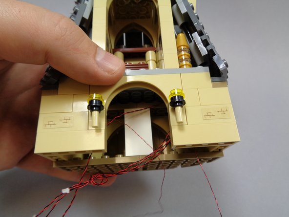 As shown in the second and third photos, mount the pre-lit wall torches and re-attach the wall section parts you removed earlier.