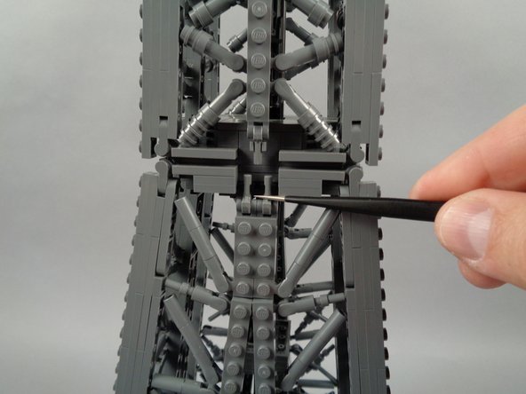 As shown by the green arrow in the first photo for this step, begin by removing the 2x4 LEGO plate at the top center of the lower panel.