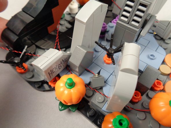 As shown in the third photo for this step, re-attach the 1x2 tombstone, holding the LED light wires in place.