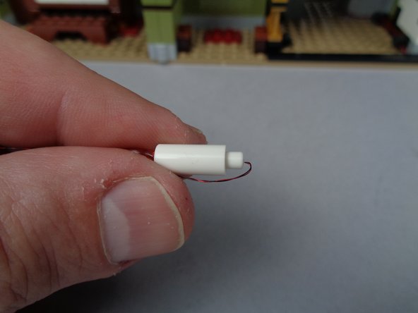 As shown in the second and third photos for this step, carefully bend the candle light wire for each candle so it points toward the top of the candle and so there is a small amount of excess wire under the bottom of the candle.  This helps prevent the wire from being torn when you re-attach the candles to their bases.