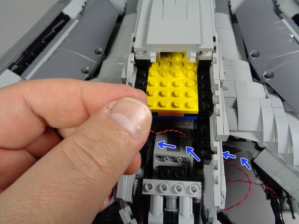 As shown by the blue arrows in the third photo, carefully pass the light wire toward the head, up through the opening in the bottom of the head, and into the main head section.  Make sure the wire passes under the chin.