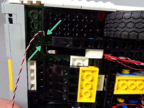 Using a brick separator, carefully loosen the black slope attached to the frame of the vehicle.  Loosen it just enough to allow the wire for the door switch to pass underneath.