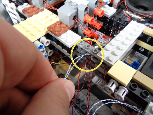 As shown in the second and third photos, pull the laser light wires up through the center of the Falcon and pass the wires through the stud holes in the Technic bricks at the center of the Falcon core.