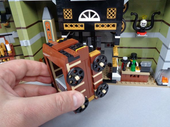 As shown in the photos for this step, replace the elevator in its shaft and re-attach the two side brackets that hold it inside the shaft.