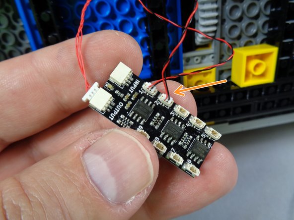 As shown by the orange arrow in the second photo for this step, connect the second hood strobe light to plug #2 on the BRANCH09X adapter.