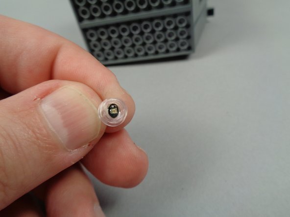 Take one of the round transparent 1x1 plates you removed from the &quot;Brick Parts&quot; bag earlier, and feed the LED light wire through the larger hole.